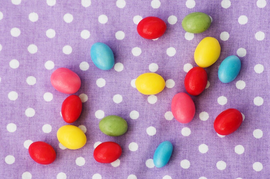 Colourful sugar eggs on a spotted cloth (seen from above)