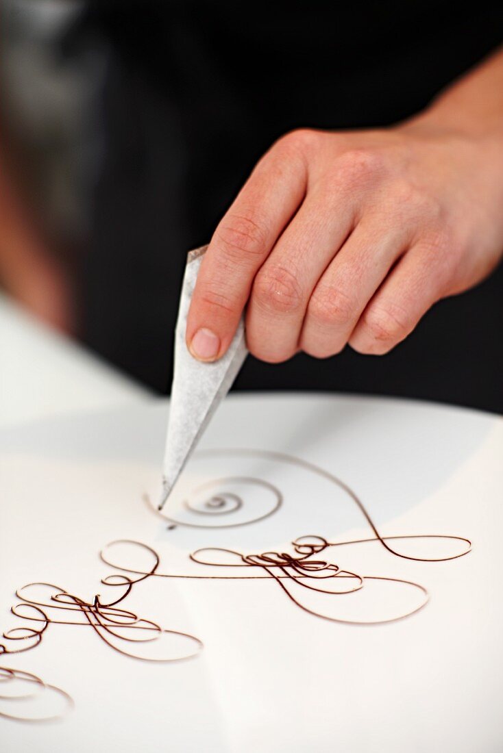 A white plate being decorated with writing icing
