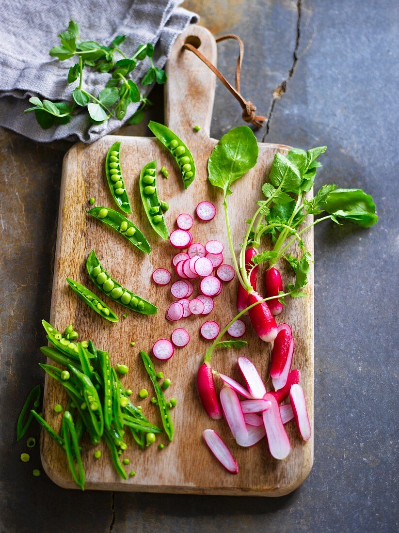 Ingredients for spring salad with peas and radishes on a chopping board