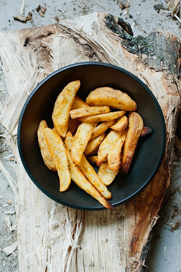 Hausgemachte Pommes frites in Schüssel auf Holzbrett