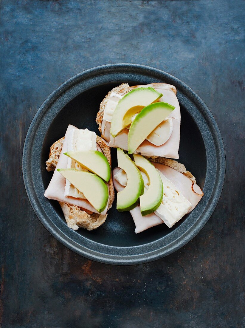 An open sandwich topped with turkey ham, Camembert and avocado