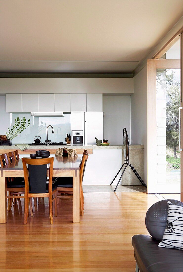 Dining area in front of white fitted kitchen with same-level access to terrace