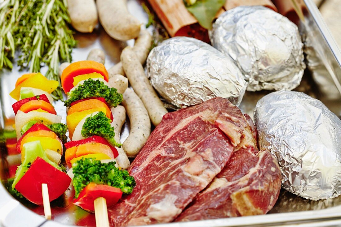 Beef steaks, baked potatoes, sausages and vegetable skewers ready for a barbecue