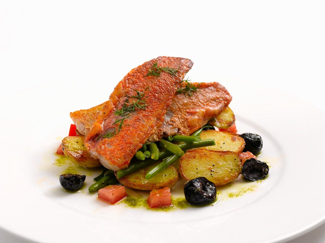 Red mullet fillet on a bed of potatoes with green beans and olives