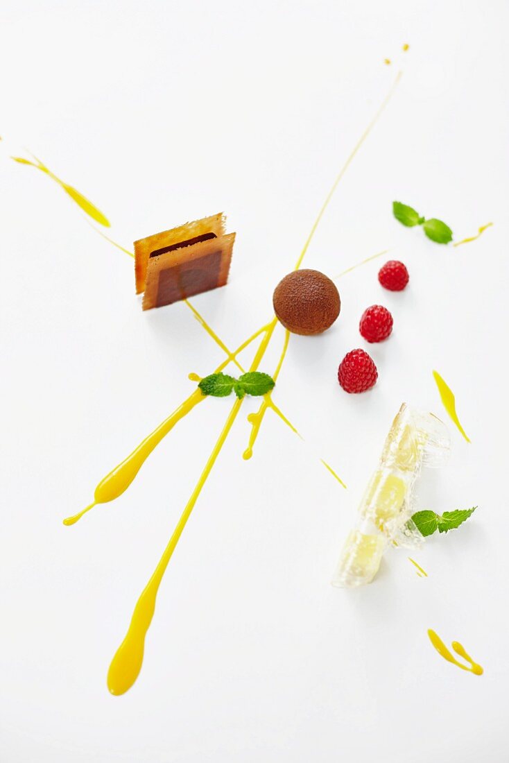 A dessert platter with chocolate truffles, raspberries and mango sauce