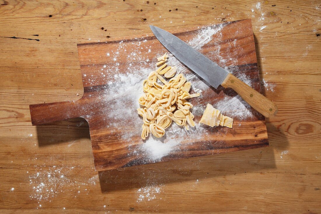 Pasta dough, cut into strips, on a chopping board
