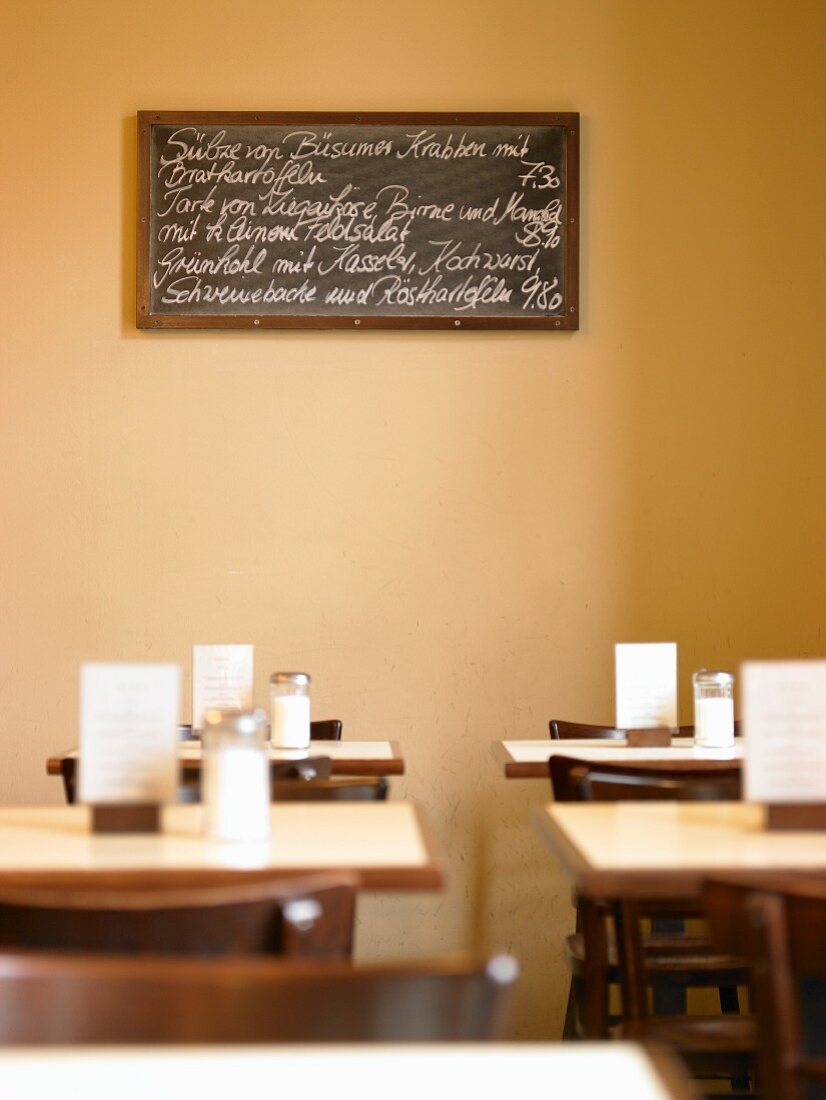 Handgeschriebene Speisekarte auf schwarzer Schiefertafel in sonnigem Essraum eines Restaurants