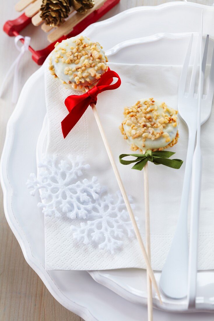 Two Christmas cake pops decorated with white cooking chocolate and nut brittle
