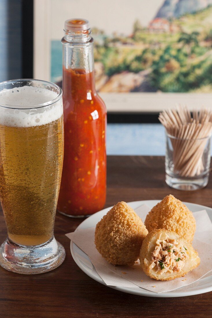 Coxinhas (frittierte Hähnchenkroketten, Basilien) mit Würzsauce und Bier