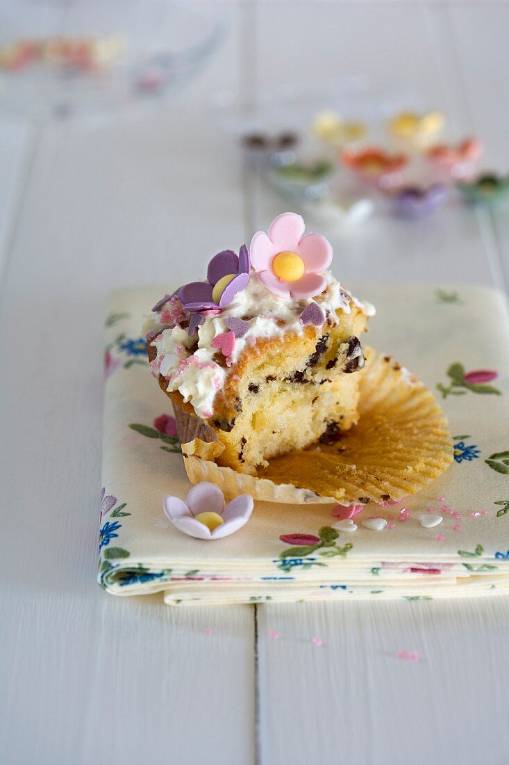 A half-eaten cupcake decorated with sugar flowers