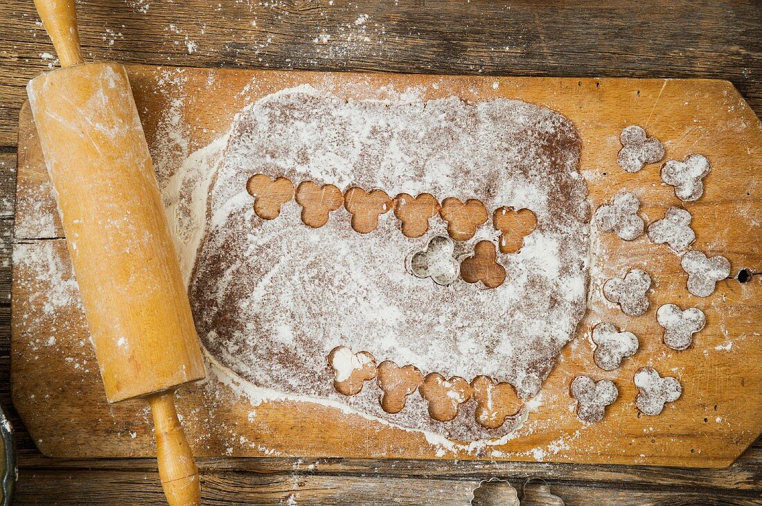 Biscuit dough, cut-out biscuits and a rolling pin on a chopping board