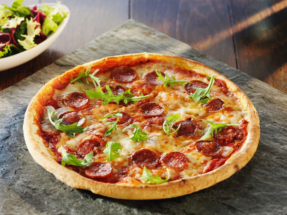 Pizza mit Peperoniwurst auf Holztisch