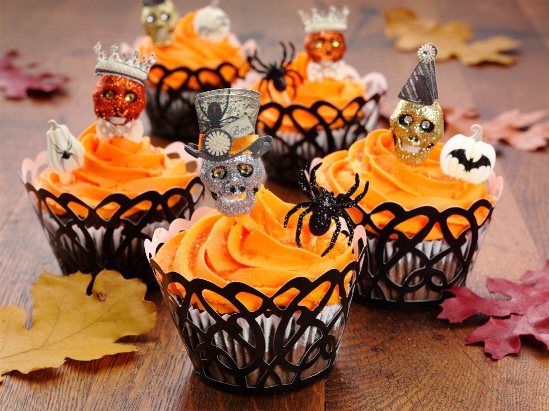 Halloween-Cupcakes auf Eichentisch mit Herbstlaub