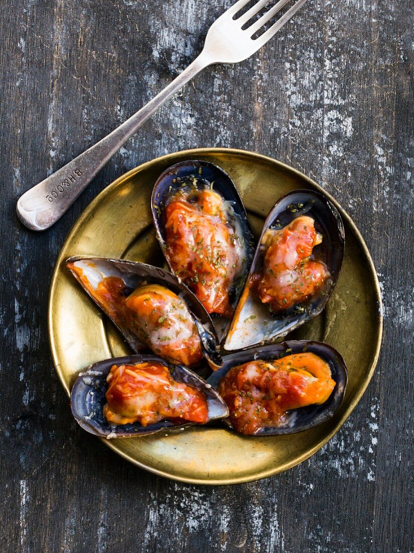 Spicy gratinated mussels on a gold-coloured plate
