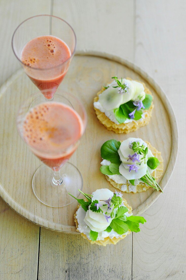 Canapes with vegetables and herbs and glasses of carrot juice