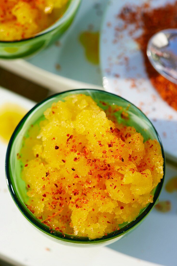 Mango granita with chilli powder in a green glass bowl (seen from above)