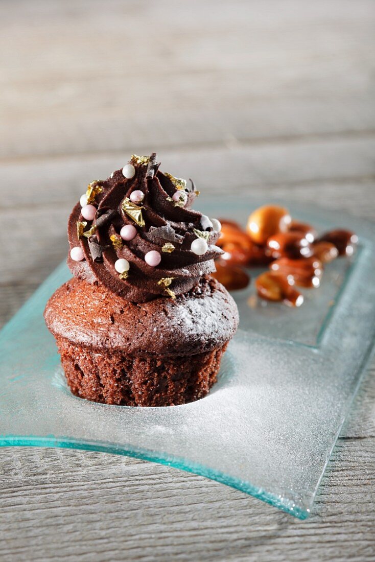 Schokoladen-Cupcake mit Zuckerperlen und Blattgold