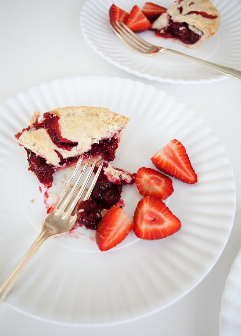 Two slices of strawberry pie with fresh strawberries