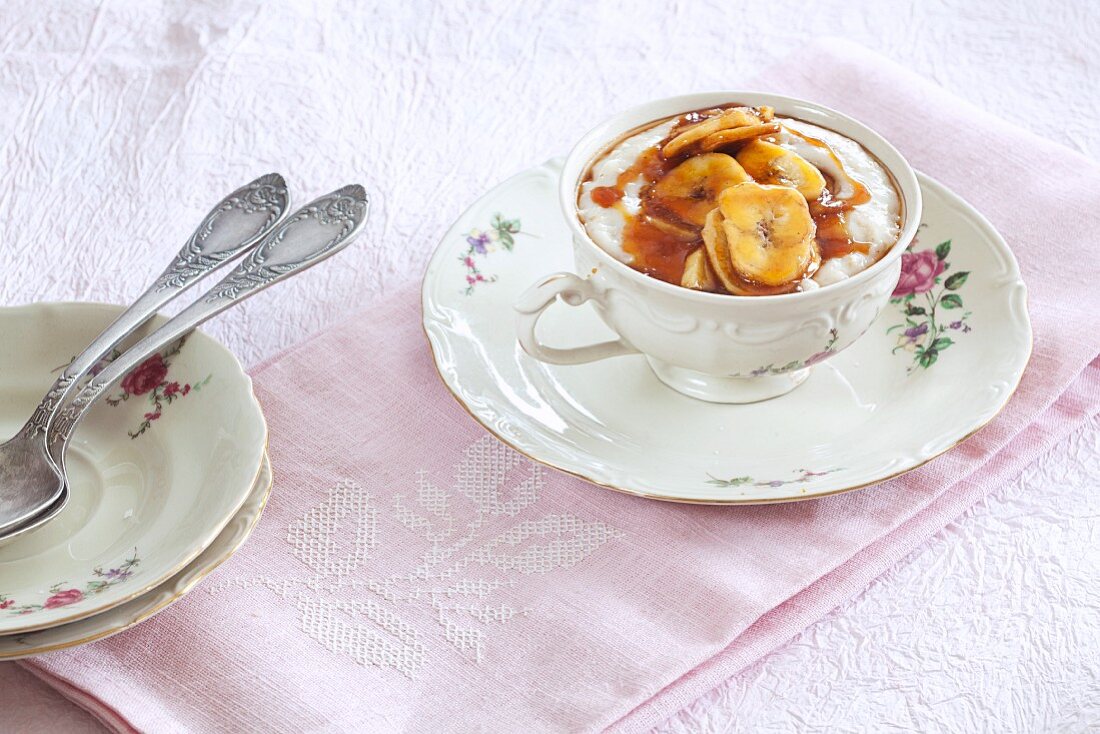 Porridge (Haferflockenbrei) mit Banane und Karamellsauce in geblümter Kaffeetasse