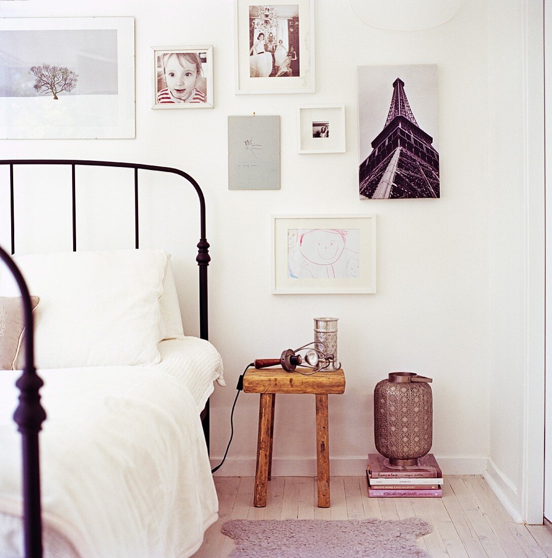 Vintage-style metal table next to rustic bedside table below photos and drawings on wall