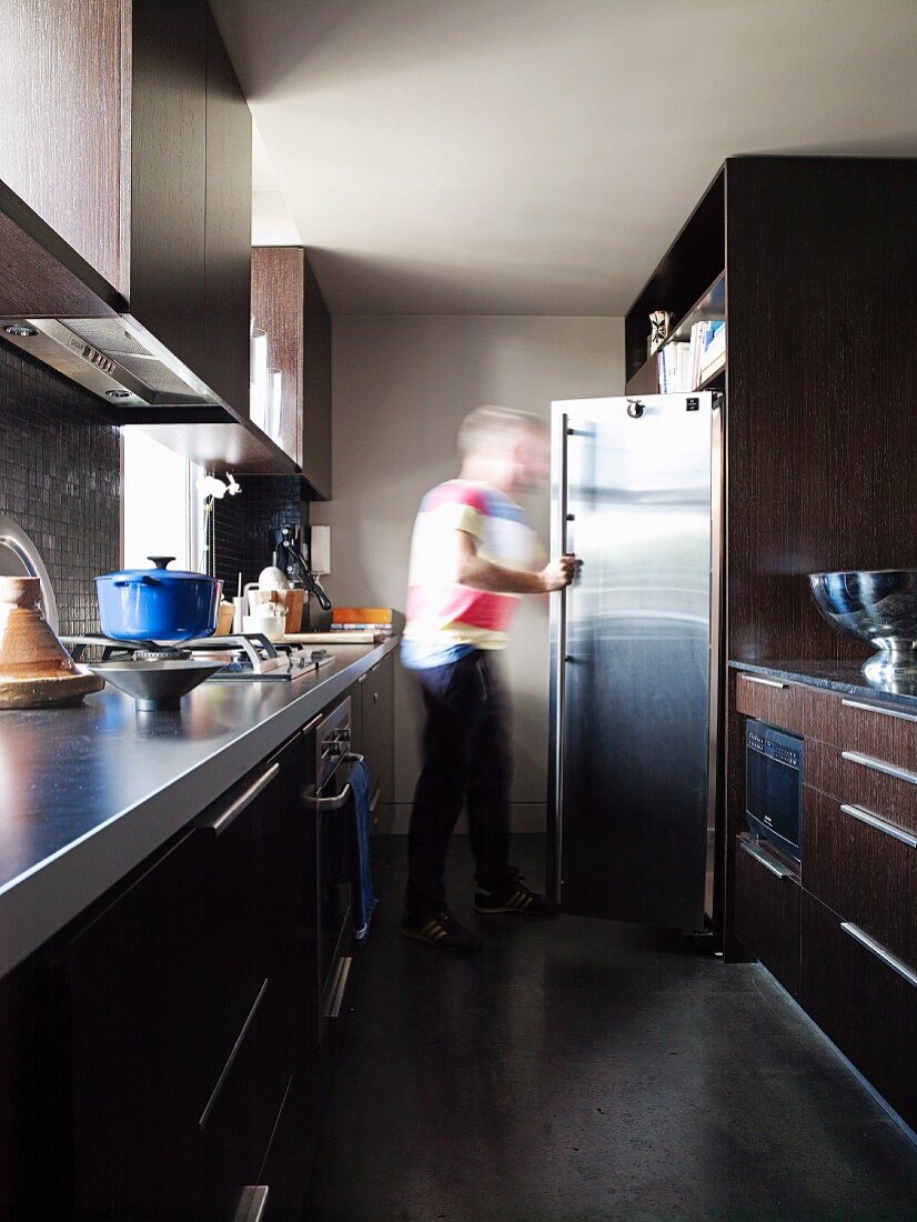 Schmale Küche mit zweiseitigen Küchenzeilen; Person am Kühlschrank