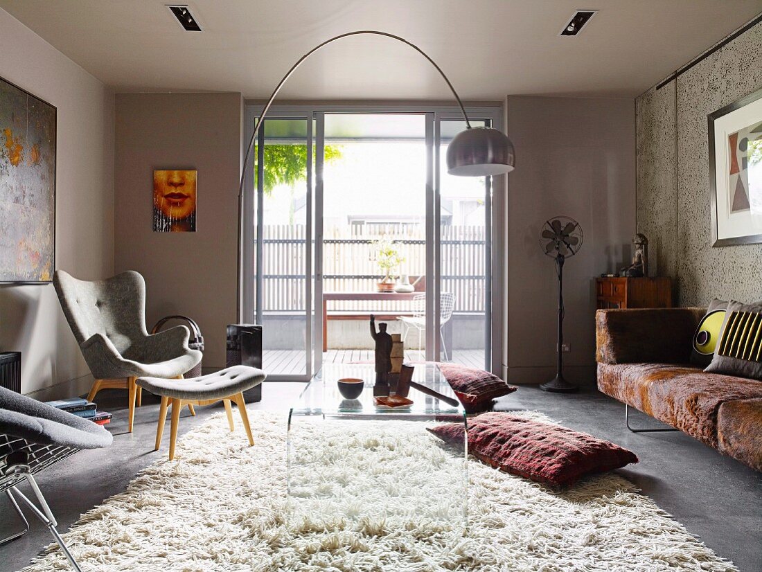 Transparent plastic coffee table and armchair with matching footstool on flokati-style rug