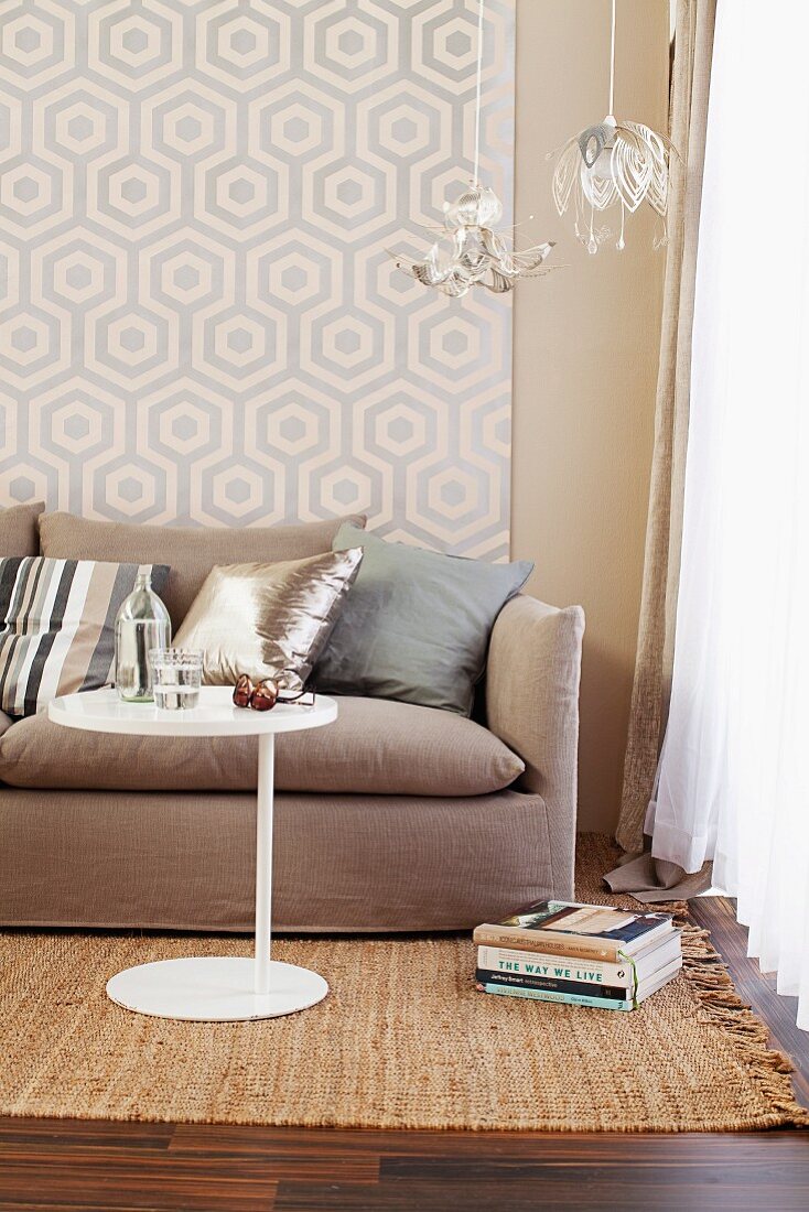 Seating area with patterned wallpaper, sofa, side table & delicate pendant lamps