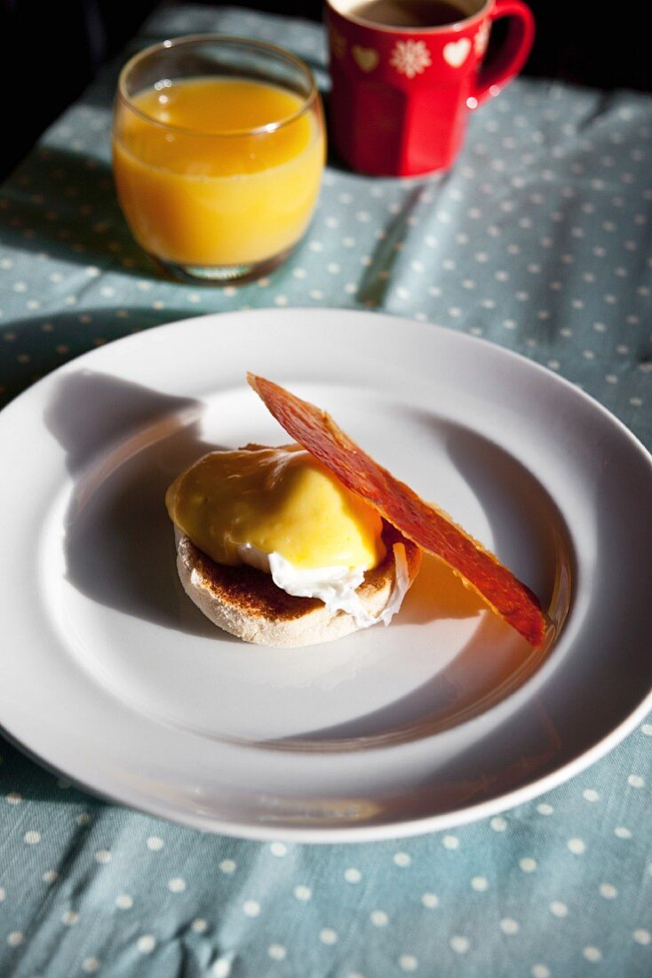 Eggs Benedict with a slice of crispy Parma ham on a breakfast table