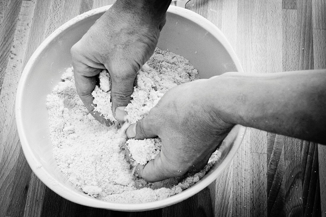 Ingedients for shortcrust being mixed by hand (black-and-white image)