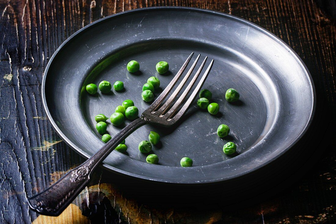 Peas and a fork on a metal plate