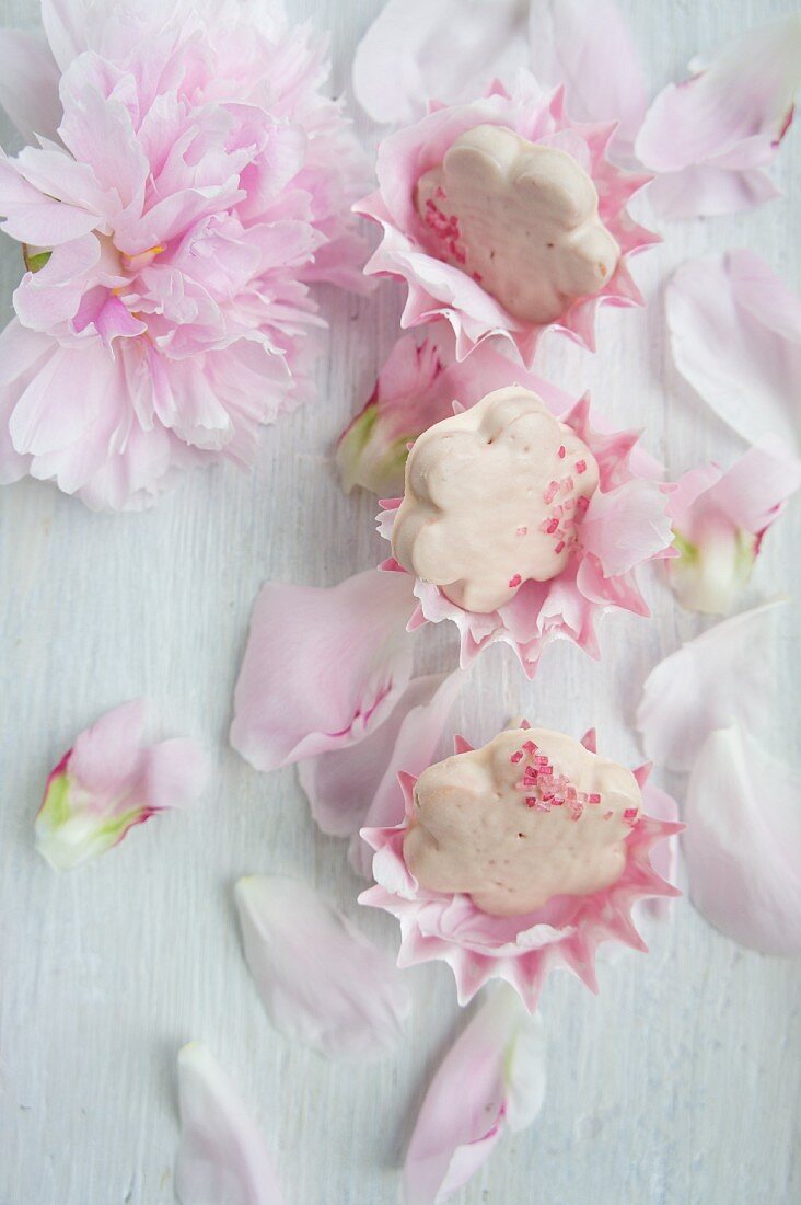 Flower-shaped biscuits with rose icing scattered with peony petals