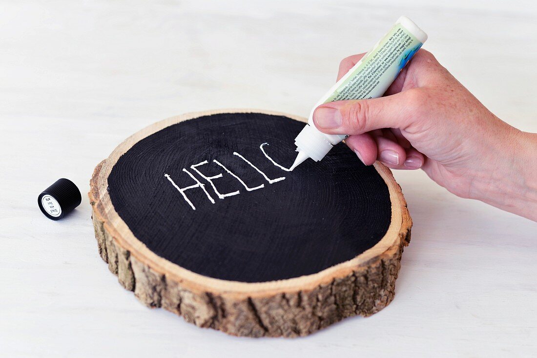 Writing in white on black-painted surface of log slice