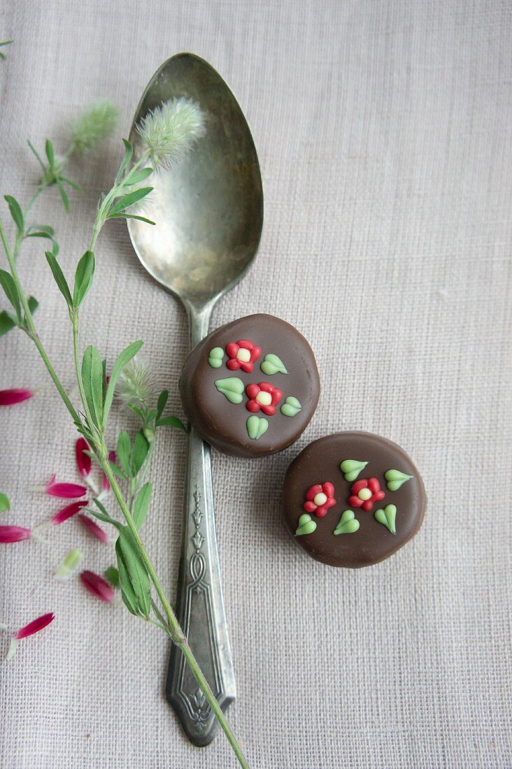 A silver spoon and pralines decorated with flowers