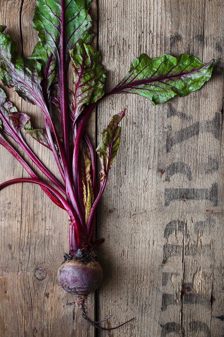 A beetroot with leaves on a rustic wooden surface