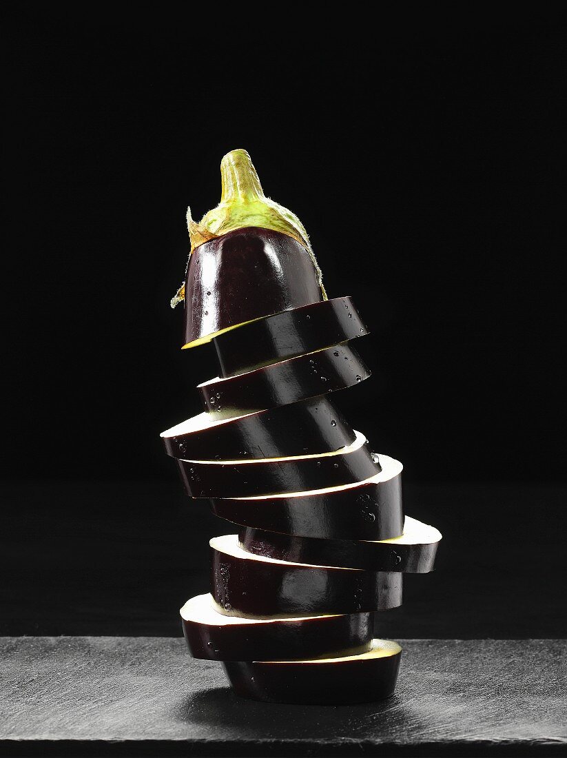 A stack of aubergine slices on a stone surface