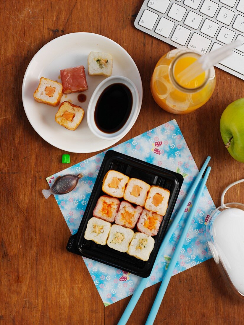 Sushi, Orangensaft und Apfel im Büro