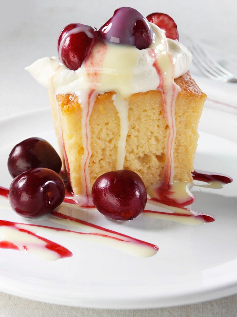 A sponge cake with caramel sauce, cream and cherries