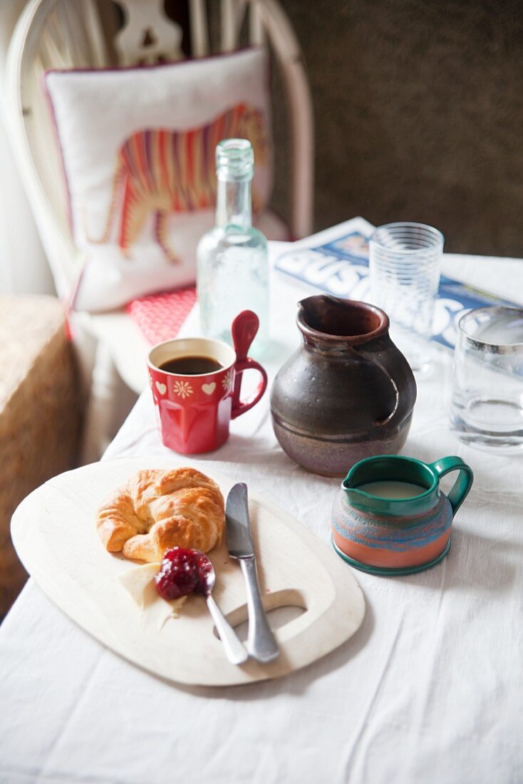 Breakfast with croissants, jam, coffee, newspapers