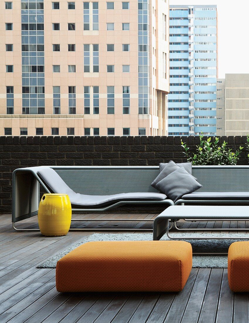 Designer lounger and ottomans on loft terrace; view of cityscape in Johannesburg, South Africa