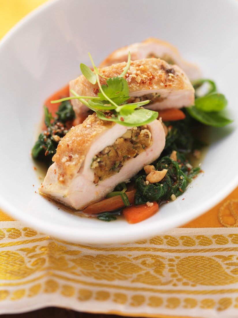 Stuffed chicken breast on a bed of spinach with cashew nuts