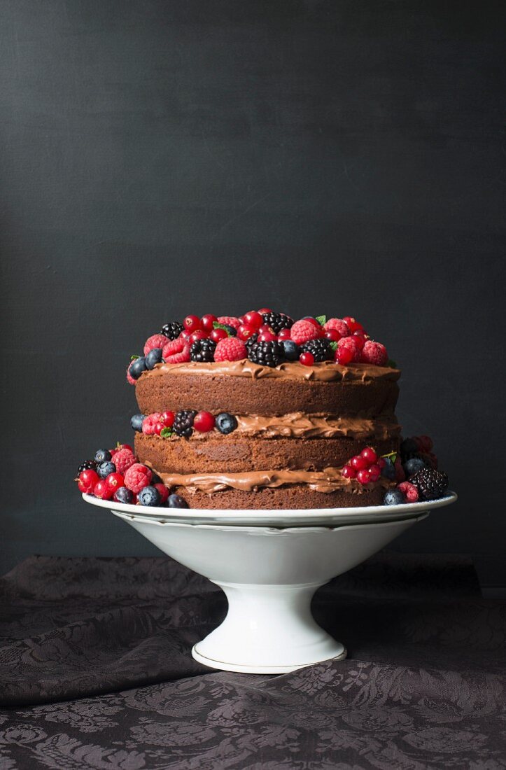 A layered cream chocolate cake decorated with fresh berries