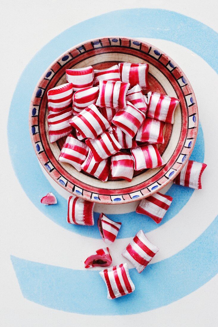 Red-and-white striped peppermint bonbons in a ceramic bowl