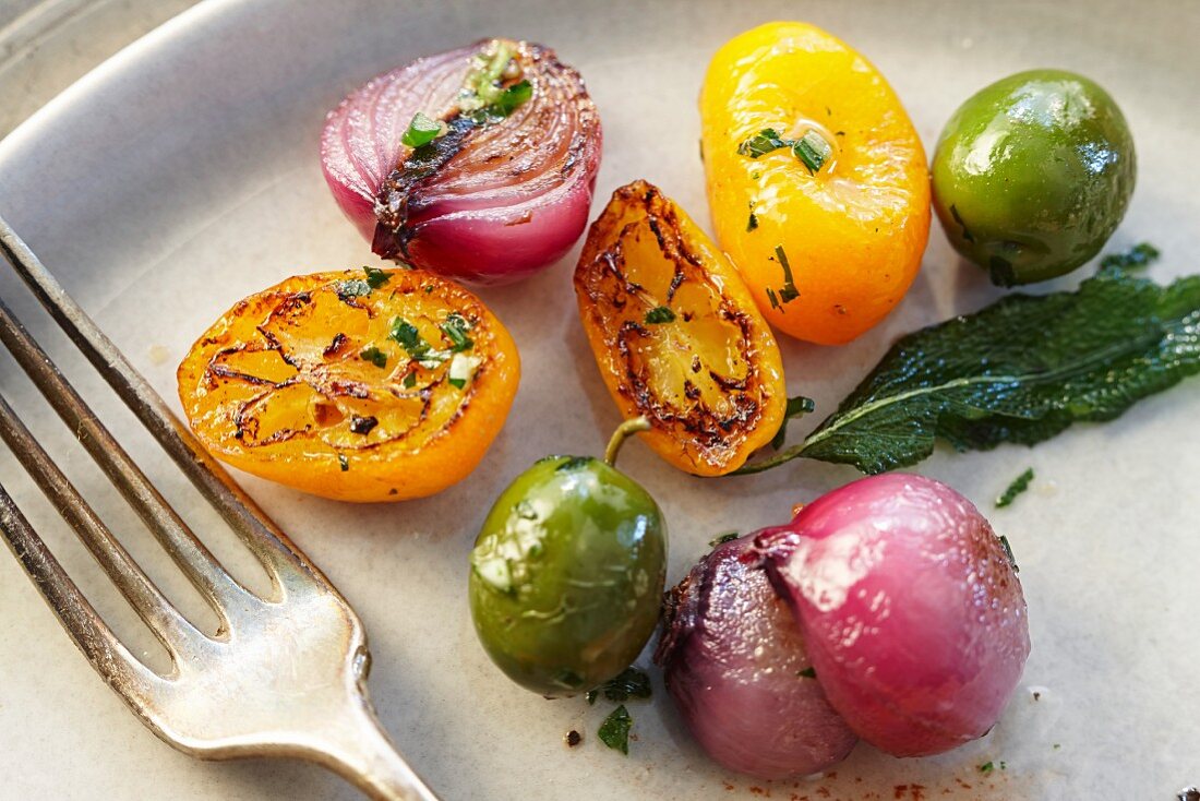 Roasted onions, yellow tomatoes, capers and sage (close-up)