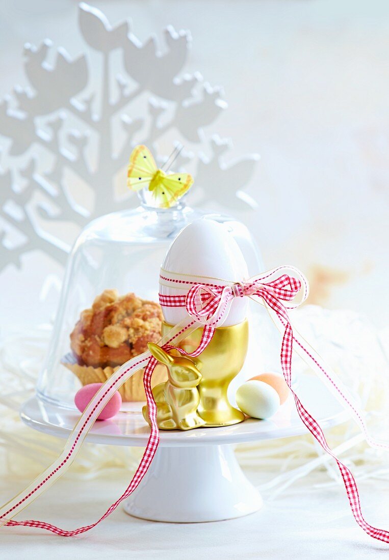 An egg in a golden egg cup and a muffin for Easter