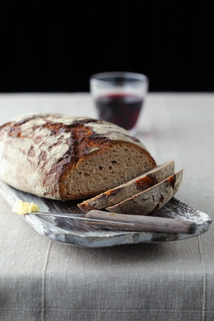 Angeschnittenes Brot mit Rotwein, sowie Messer mit Butter