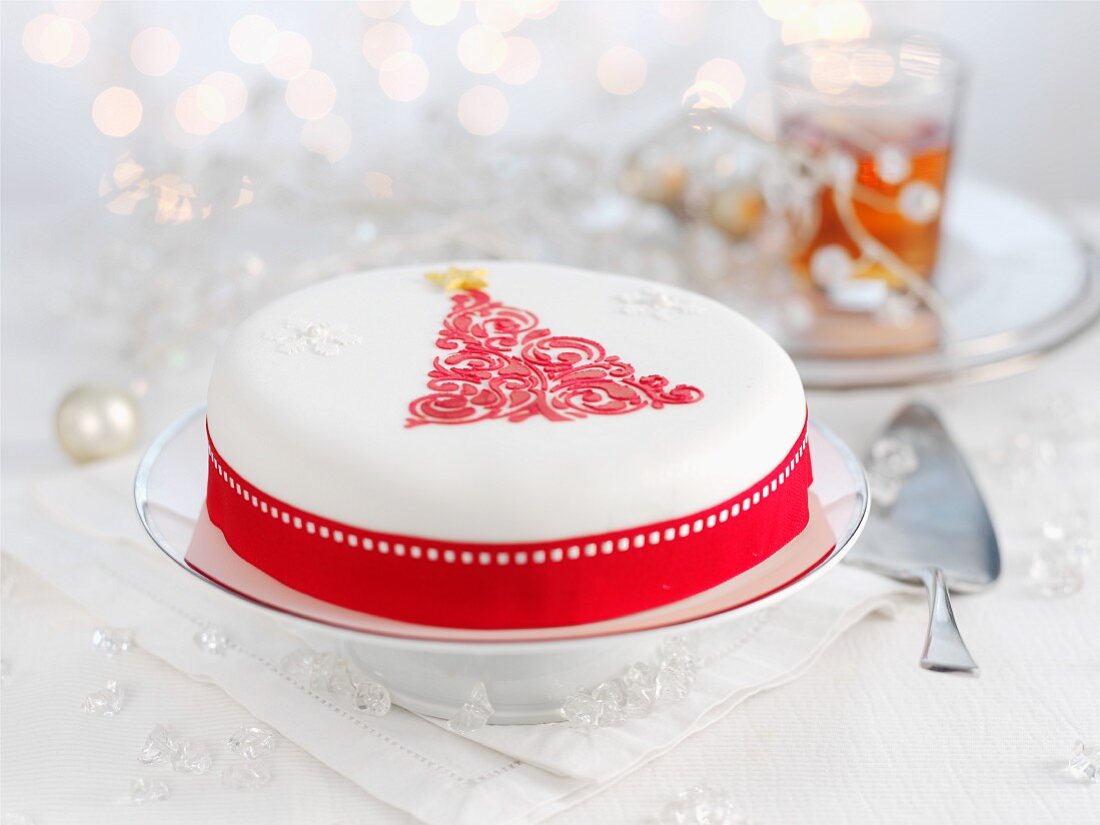 A white Christmas cake decorated with a red Christmas tree