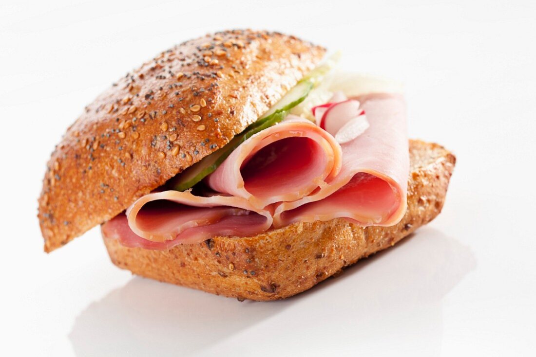 A wholemeal bread roll filled with ham, cucumber and radishes