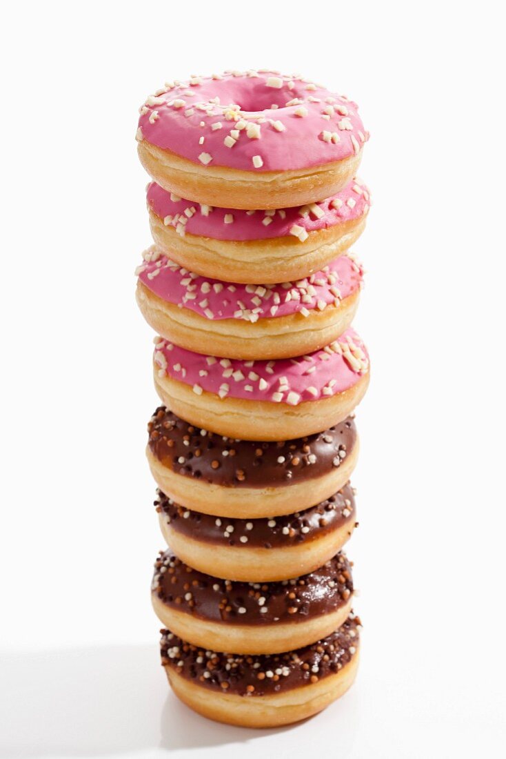 A stack of doughnuts with chocolate icing and pink icing