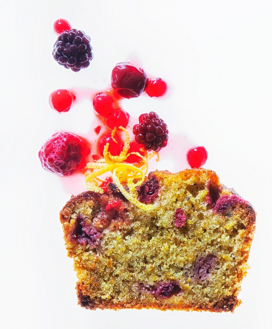 A slice of pistachio cake with berries and lemon zest
