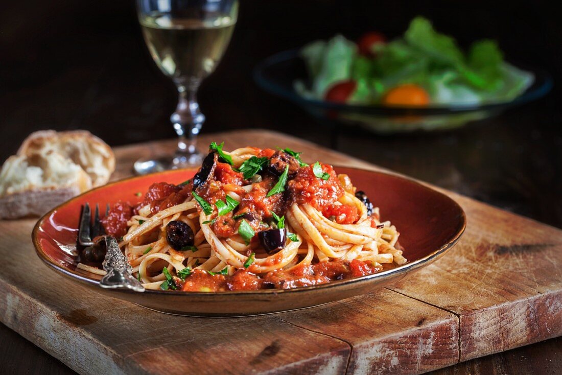 Spaghetti Puttanesca (Oliven, Kapern, Tomaten und Petersilie) mit Weißwein, Brot und Salat